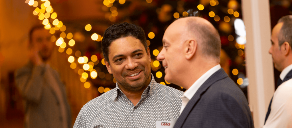 Andrew Scott is seen speaking with Piers Linney at the Business Leader Awards, set against a festive background. The image highlights a professional networking moment at a prestigious business event.